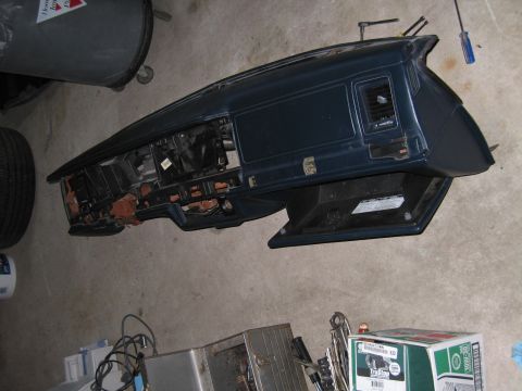1991 Ford LTD Crown Victoria - dark car dashboard assembly removed from the vehicle and lying on the garage floor with wiring, beside tool boxes.
