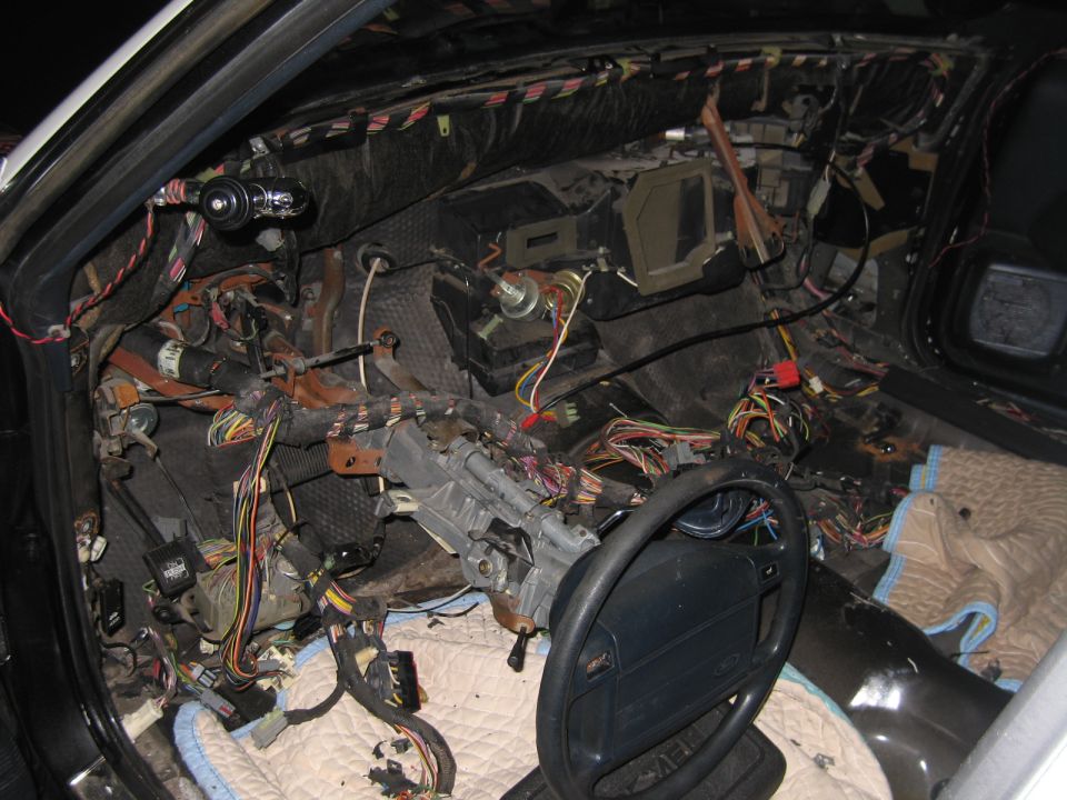 Stripped car dashboard cavity showing exposed wiring and steering column