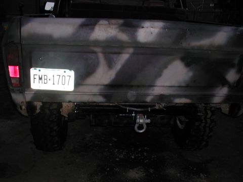 1979 Ford Bronco - The rear of a camouflage-painted truck is shown with a license plate and tow hitch.