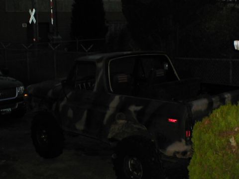 1979 Ford Bronco - A camouflaged SUV is parked next to another vehicle, with a railroad crossing signal in the background.