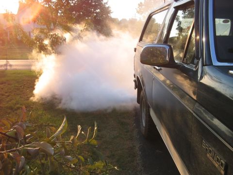 1992 Ford Bronco - 1992 Ford Bronco side view with smoke billowing from the exhaust on a sunny day.