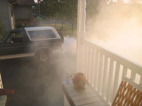 1992 Ford Bronco - A dark colored Ford Bronco is seen from the side, emitting a large cloud of smoke.