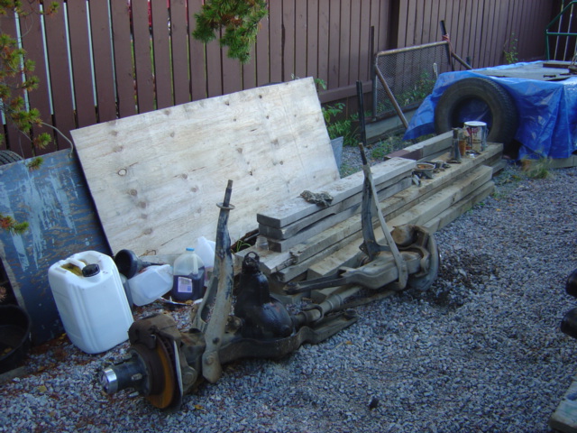 Front axle assembly with disc brakes and suspension components, resting on gravel