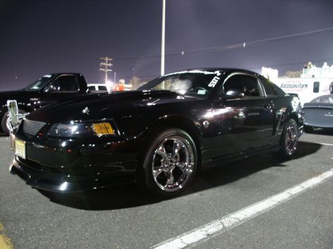 2001 Mercury Grand Marquis - A black Ford Mustang is parked at an outdoor event at night, with other vehicles nearby.