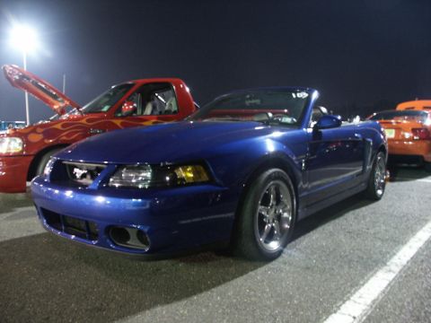 2001 Mercury Grand Marquis - A blue convertible sports car is parked at a night event, with other vehicles visible in the background.