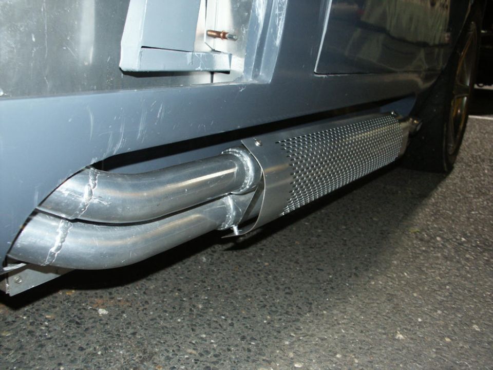Close-up of dual exhaust pipes with perforated heat shield on a vehicle