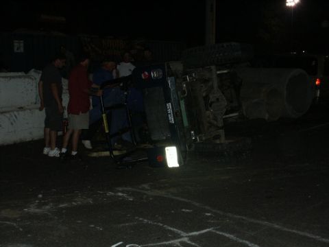 2001 Mercury Grand Marquis - People gather around an overturned vehicle at a nighttime event.