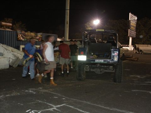 2001 Mercury Grand Marquis - A dark blue Jeep Wrangler is seen from the rear at night, with people standing around.