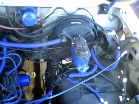 1986 Ford Bronco - Engine bay components, including a brake booster and master cylinder, are visible with custom blue hoses.