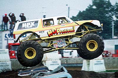 1993 Ford Bronco - A 1993 Ford Bronco monster truck, "NO PROBLEM!", is airborne over crushed cars.