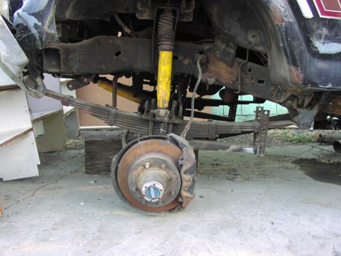 1983 Ford F-250 - The rear suspension and wheel assembly of a truck are shown, with leaf springs and a brake rotor prominent.