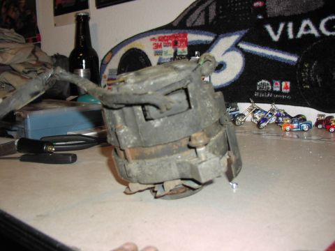 1979 Ford Bronco - A dusty automotive alternator sits on a workbench, with a beer bottle and toy vehicles in the background.