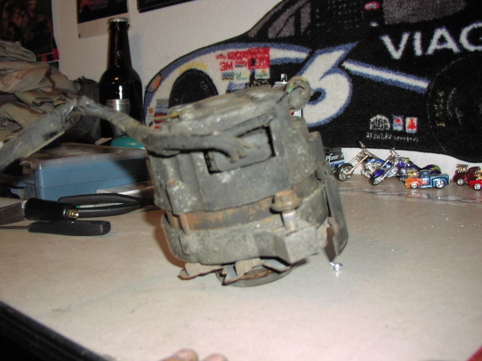 close-up of a used automotive alternator with wires attached, sitting on a table