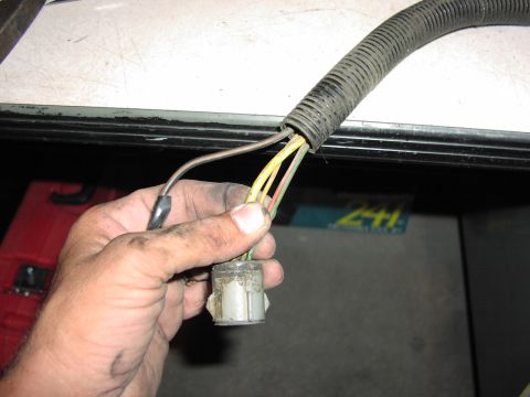 1979 Ford Bronco - Close-up of a hand holding an electrical connector with multiple wires, with a partial view of the number '241' in the background.