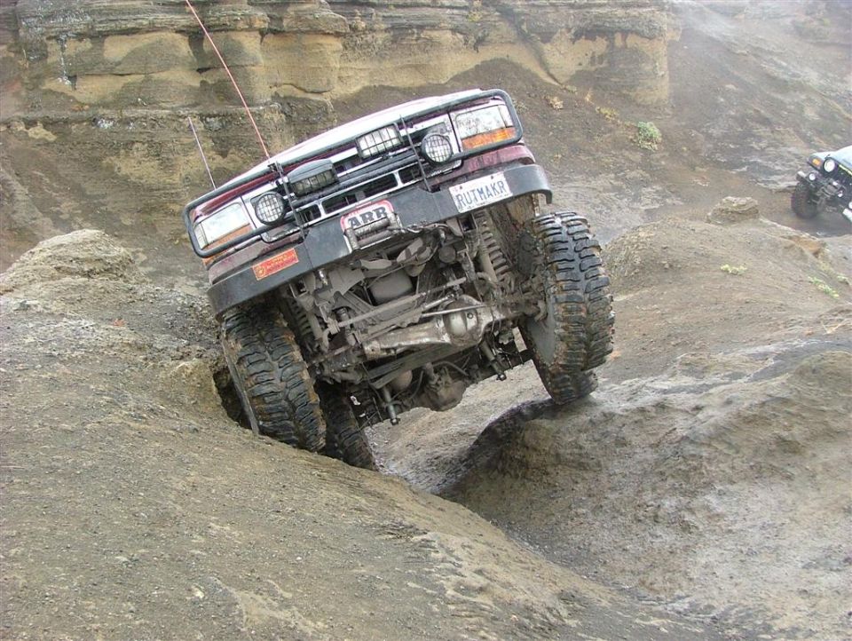 Off-road vehicle with large tires navigating a steep, rocky incline. Another vehicle is visible in the background