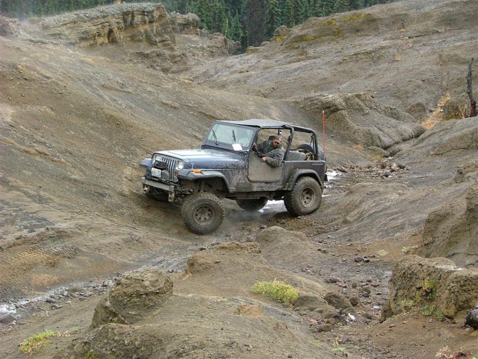 Dark blue Jeep Wrangler driving on a rocky, off-road trail