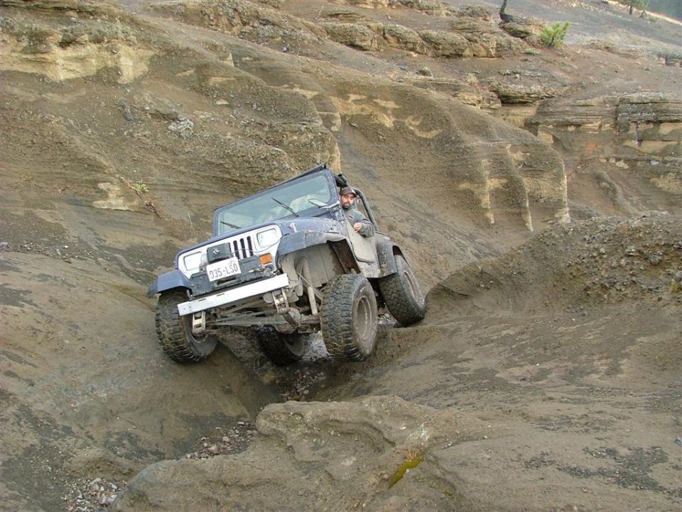 Blue Jeep Wrangler navigating a rocky, off-road trail