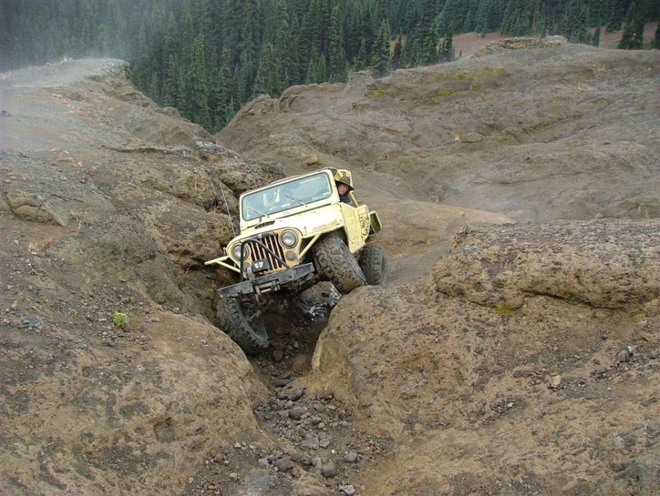 Yellow Jeep CJ-7 navigating a rocky, off-road trail