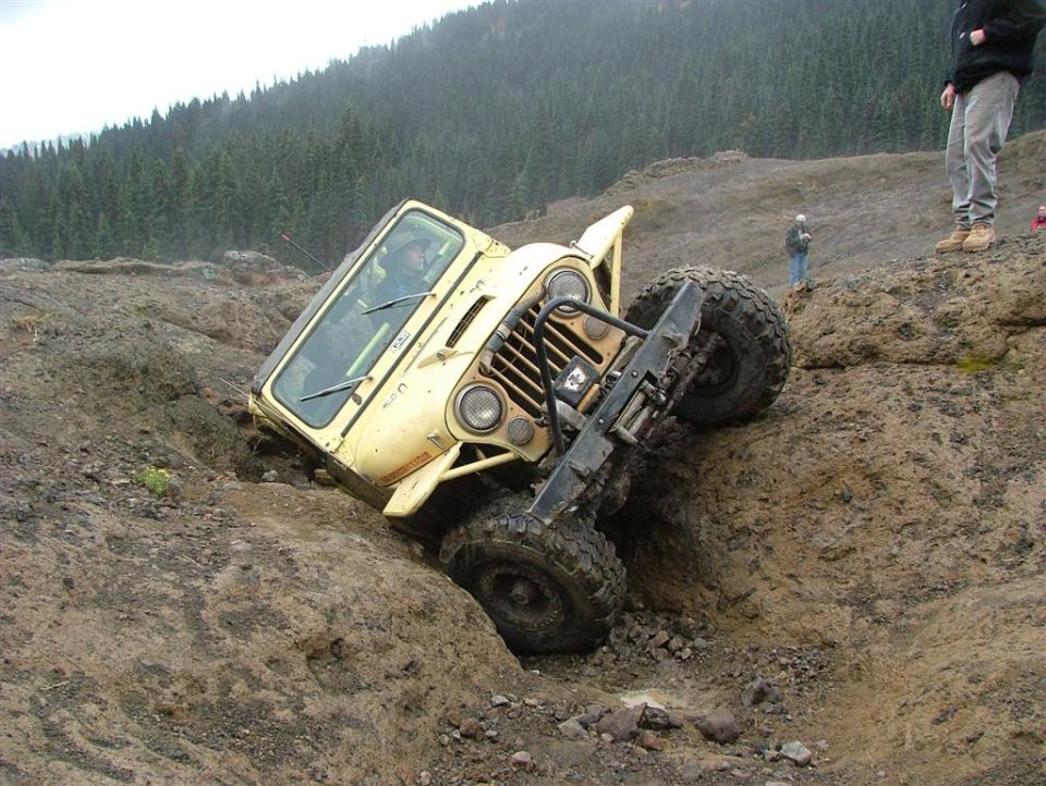Yellow Jeep CJ-5 tilted in a ditch off-roading