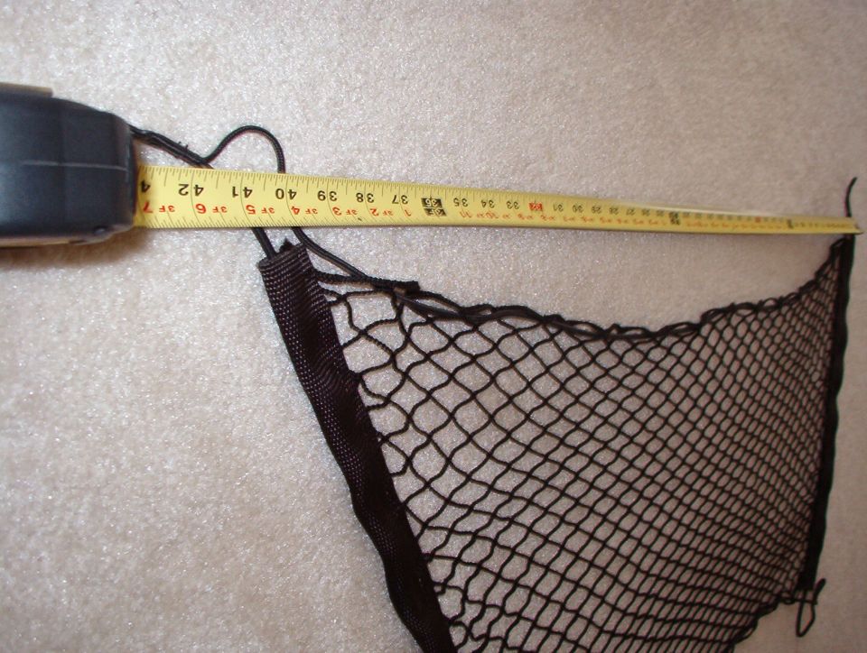 Corner of a black mesh cargo net on carpet with a tape measure reading near 40 inches