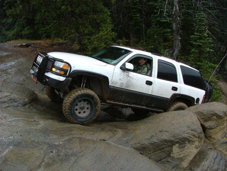White SUV with off-road tires navigating rocky terrain