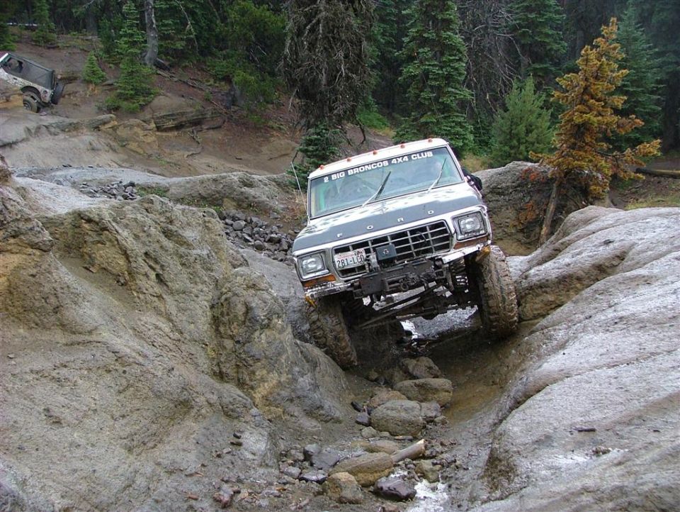 Ford truck with "BIG BRONCOS 4X4 CLUB" sticker on windshield, navigating rocky terrain