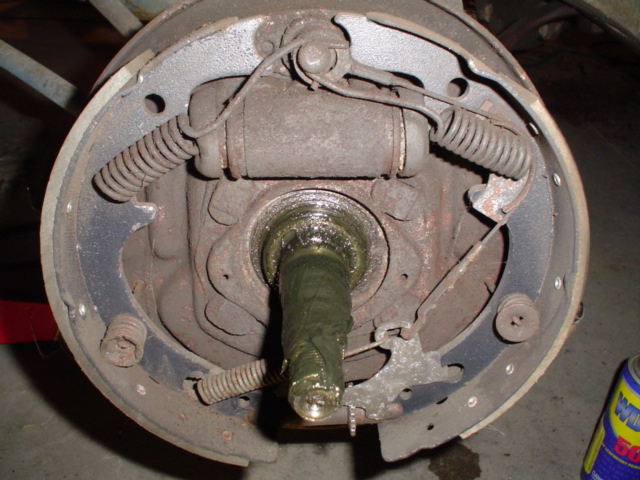Rear drum brake assembly with drum removed, showing shoes, springs, wheel cylinder, and greasy axle shaft