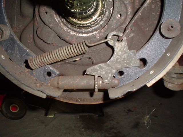 Disassembled drum brake backing plate showing shoes, springs and wheel cylinder