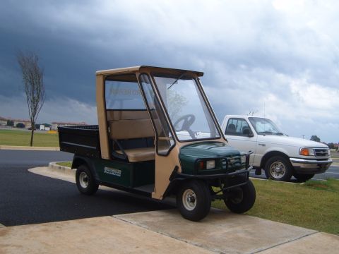 1988 Ford Bronco - A utility vehicle with a tan roof and a pickup truck are parked side-by-side under a stormy sky.