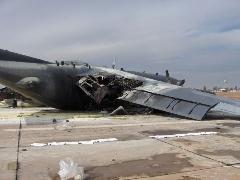 1988 Ford Bronco - A severely damaged aircraft lies on a concrete surface, with its wing fractured and debris strewn around the scene.