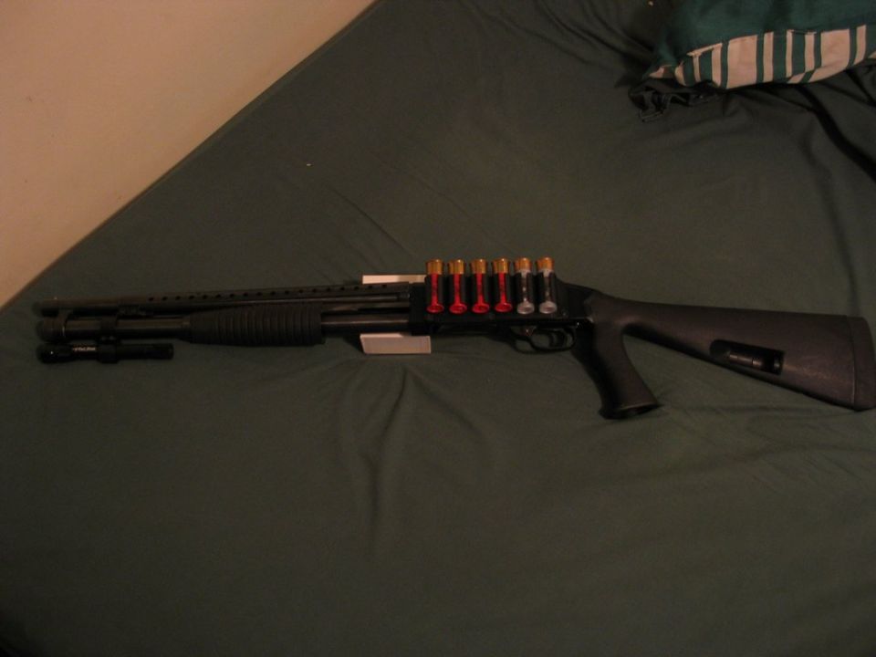 shotgun with a side saddle holding six shells and a flashlight mounted on the barrel