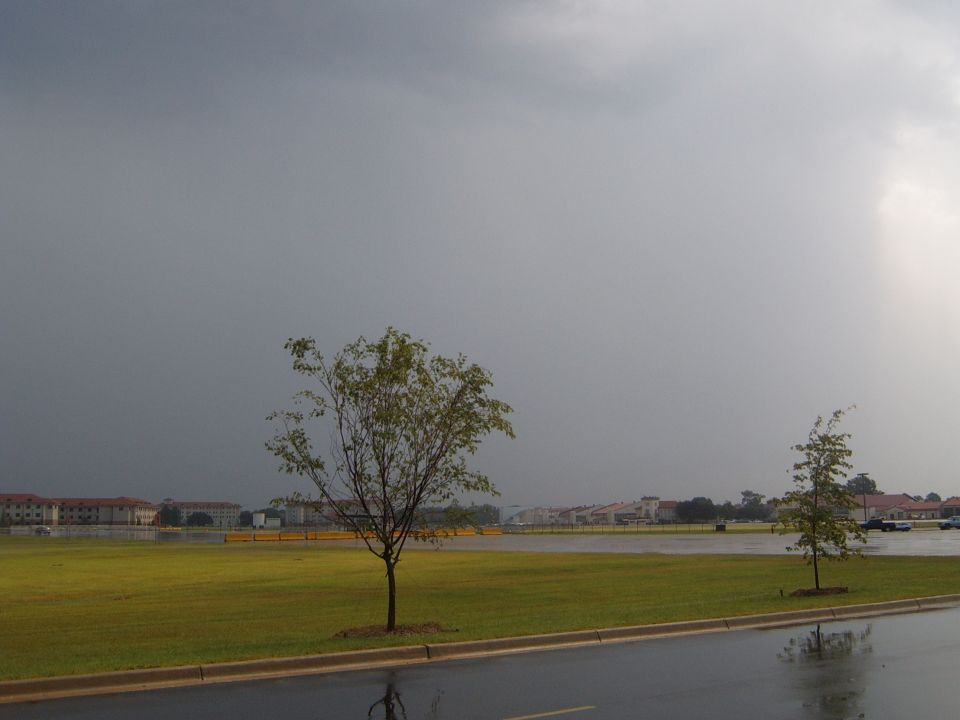 Stormy sky over a grassy field with buildings in the distance