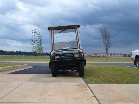 1988 Ford Bronco - A green utility vehicle with a cab is parked on a sidewalk, with a white truck visible to the right.