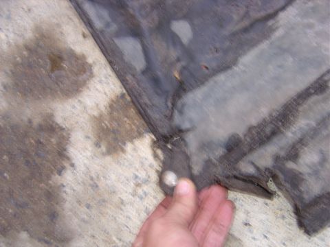 1987 Suzuki Samurai - A hand is shown holding the edge of a black rubber mat, revealing a metal grommet detail.