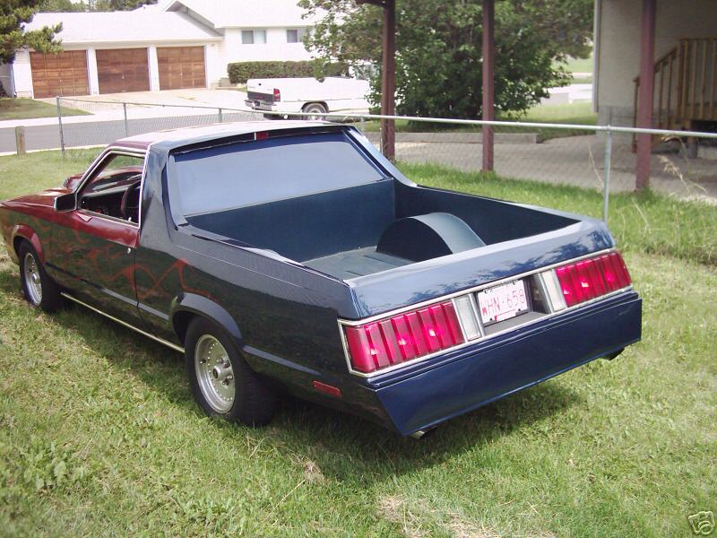 Dark blue flamed coupe-utility pickup on grass, rear three-quarter view