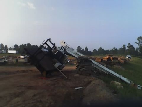 1979 Ford F-150 - A truck with a crane attachment has overturned in a construction or lumber yard area.