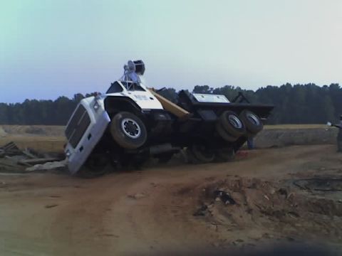 1979 Ford F-150 - A tractor-trailer truck has overturned on a dirt construction site, with its wheels in the air.