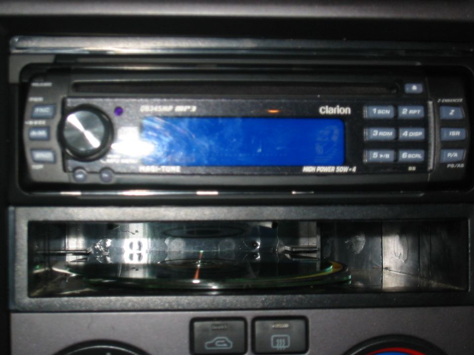 Clarion DB345MP CD head unit with blue display installed in dash, CDs in cubby below