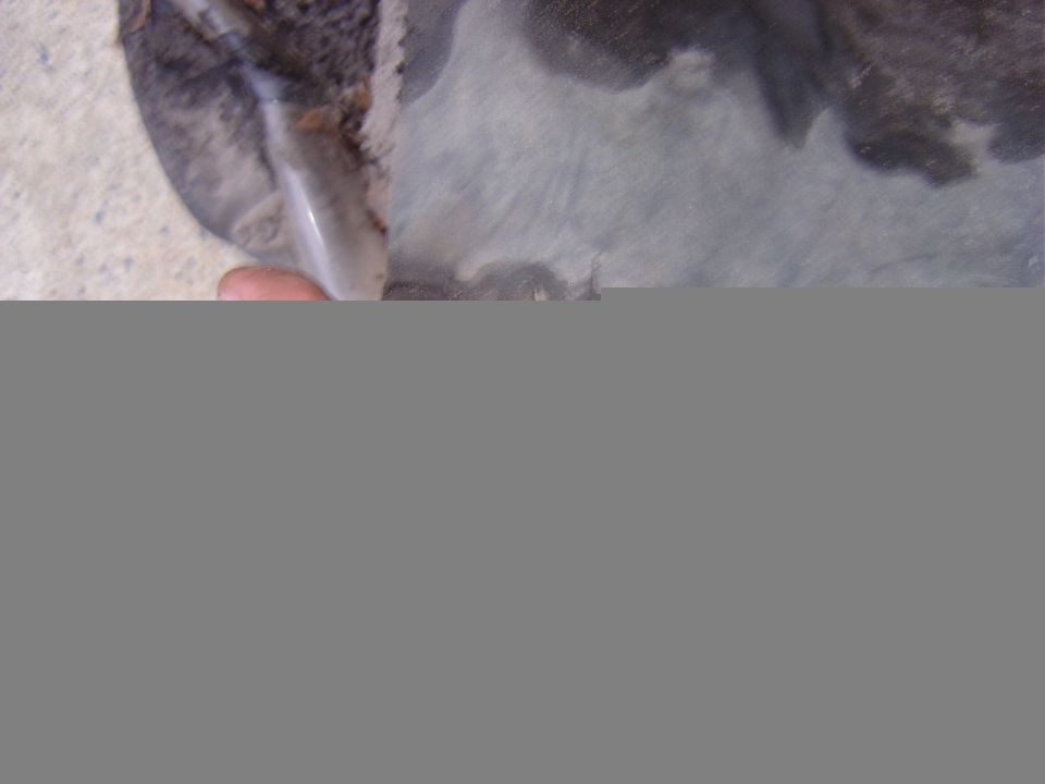 Close-up of a dirty, possibly rusted vehicle part with a hand holding it