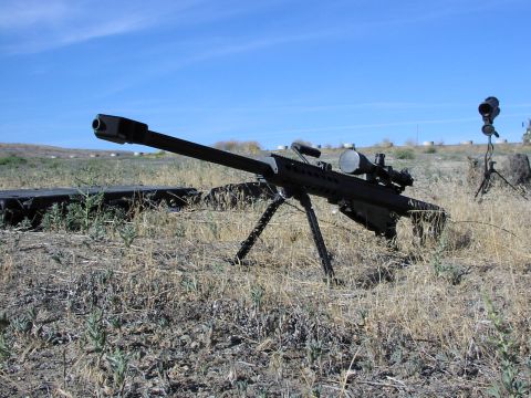 1979 Ford Bronco - A sniper rifle with a scope and bipod is positioned in a field with dry grass and a clear blue sky.