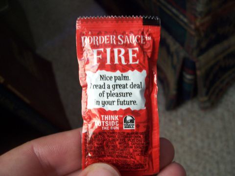 1995 Ford Bronco - A Taco Bell Fire Sauce packet is held in a hand, showing its branding and ingredients list.