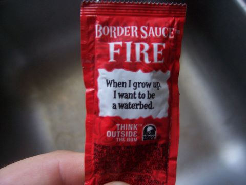1995 Ford Bronco - A Taco Bell Fire sauce packet is held in a hand against a blurred background.