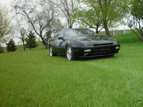 1992 Ford Probe - A black sports car is parked on a grassy hill with trees in the background.
