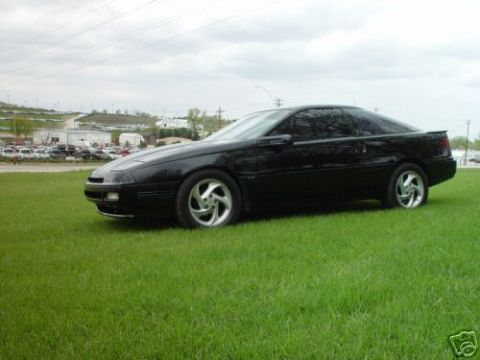 1992 Ford Probe - This black 1992 Ford Probe is parked on a lawn with a distant parking lot visible.