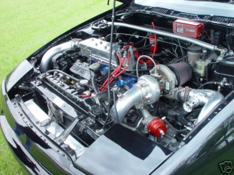 1992 Ford Probe - The engine bay of a black car is shown with custom modifications including a turbocharger and intercooler.