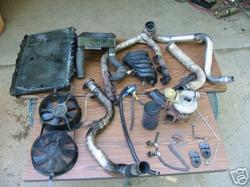 1992 Ford Probe - Various automotive engine parts are displayed on a table, including a radiator, fans, and turbocharger.