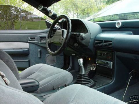 1992 Ford Probe - The interior of a car features aftermarket gauges on the dashboard and A-pillar, along with a manual transmission shifter.
