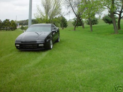 1992 Ford Probe - A black coupe is parked on a grassy hill with trees in the background. The 'SUPERMOTORS' logo is visible in the lower right corner.