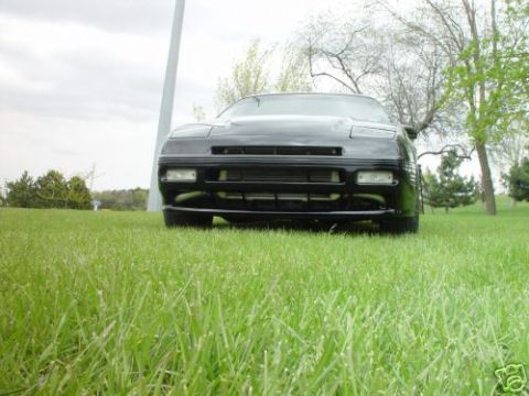 1992 Ford Probe - A black car is viewed from a low angle, sitting on a grassy field under an overcast sky.