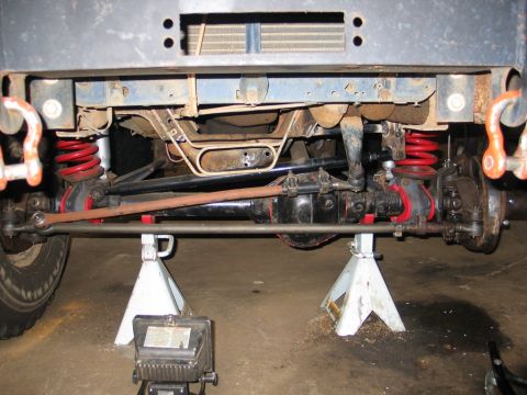 1995 Ford Bronco - Close-up view of the front suspension and steering system of a vehicle, supported by jack stands.